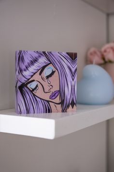 there is a purple painting on the shelf