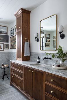 a bathroom with marble counter tops and wooden cabinets, along with pictures on the wall