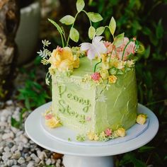 a green cake sitting on top of a white plate covered in flowers and greenery