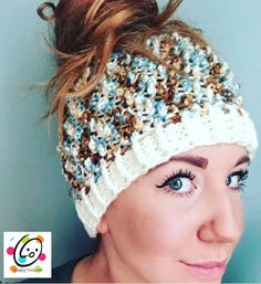 a woman with blue eyes wearing a white and brown knitted beanie headband