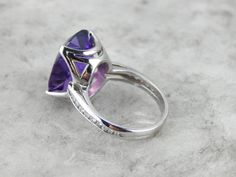 This Zambian Amethyst cocktail ring is alluring! The richness in its color, the sheer size, and the way the mounting presents the stone makes this piece unforgettable; plus this ring sits relatively low on the finger for the size of the stone! The shoulders and shank of the ring are adorned with diamonds placed within a channel. The white gold ring has beautiful cut-outs on the underside of the stone allowing plenty of light through. This piece is all about the rich beauty of this amethyst! Meta Formal Purple Sapphire Ring With Gemstone Accents, Luxury Solitaire Amethyst Ring, Purple Ring With Gemstone Accents For Formal Occasions, Luxury Polished Amethyst Ring For Wedding, Luxury Amethyst Ring For Wedding With Polished Finish, Fine Jewelry Open Amethyst Ring For Formal Occasions, Formal Amethyst Crystal Ring With Accent Stones, Amethyst Crystal Ring With Accent Stones For Formal Occasions, Formal Purple Crystal Ring With Prong Setting