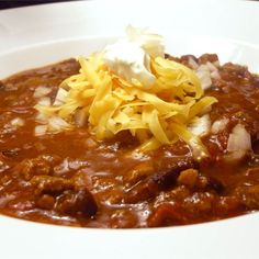 a white bowl filled with chili and cheese