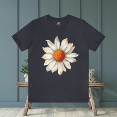 Elevate your style with our Large Daisy Unisex T-Shirt. This classic tee features a prominent large daisy design on the front, offering a clean and stylish look. Available in a wide range of sizes and colors, this versatile tee is the perfect addition to any wardrobe. #16 Boho Classic unisex jersey short sleeve tee fits like a well-loved favorite. Soft cotton and quality print make users fall in love with it over and over again. Ribbed knit collars to bolster shaping. Shoulders are tapered for a better fit over time. Dual side seams hold the garment's shape for longer. Fabric Details Made with 100% Airlume combed and ring-spun cotton, a lightweight fabric (4.2 oz/yd² (142 g/m²)) that is easy to layer, breathable. Perfect for active and leisure wear. Style Features The retail fit is perfect Cotton Short Sleeve T-shirt With Sunflower Print, Casual Daisy Print Crew Neck T-shirt, Casual Cotton T-shirt With Sunflower Print, Summer Daisy Print Short Sleeve T-shirt, White Cotton T-shirt With Daisy Print, Sunflower Print Graphic Tee, Graphic Tee With Sunflower Print And Crew Neck, Graphic Tee With Sunflower Print And Short Sleeves, Summer Crew Neck T-shirt With Daisy Print