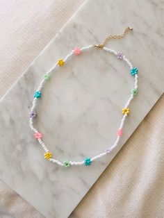 "This hand beaded flower necklace features rainbow or pastel flowers and measures 16\" at its smallest. Necklace is adjustable up to 18\" I love this necklace layered with other gold chains or worn alone to spruce up jeans and a t-shirt. Strung on elastic jewelry string and has a gold plated lobster clasp closure. Message me with any questions!" Dainty Multicolor Flower Necklace, Dainty Beaded Necklaces For Spring Gift, Spring Gift Dainty Beaded Necklaces, Spring Gift Beaded Necklaces With Tiny Beads, White Necklaces For Jewelry Making In Spring, Spring Gift Beaded Necklace With Tiny Beads, Dainty Beaded Necklaces For Spring, Dainty Spring Necklace With Round Beads, Trendy Adjustable Flower Necklace With Colorful Beads