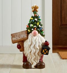 a small christmas tree sitting next to a welcome santa figurine holding a sign