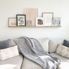 a living room with a white couch and several pictures on the wall above it,