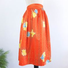 Amazing vintage 80's orange floral satin skirt with blue and yellow flowers print, dotted and pinstripe. This high waist circle skirt has retro style, it's 80's summer midi full skirt, it has yoke and side buttons and zip closure. The skirt is polyester fabric but only retains the old size label, is a used skirt and is not perfect for its age and delicate fabric, has some small loose threads and a small stain, but as its print is so striking is not much appreciated. The modern size is Small, the Orange Floral Print Long Skirt, Spring Orange Relaxed Skirt, Spring Orange Relaxed Fit Skirt, Retro Floral Print Summer Skirt, Retro Floral Print Skirt For Summer, Retro High-waisted Skirt For Spring, Spring Full Skirt In Orange, Retro Gathered Summer Skirt, Retro Floral Print Skirt With Relaxed Fit