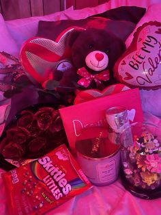 a teddy bear sitting on top of a bed next to valentine's day treats