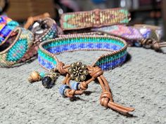 Bead Loom Leather Wrap Bracelet Blue Green Feather Blanket Boho Bracelet Bohemian Jewelry Aerieanna's Wristcraft This is a bead loom leather wrap bracelet made with naturally dyed (veggie) golden brown leather from the USA.  The beads are shades of green and blue. The button is brass plated pewter in a beaded flower design. Glass and stone dangles with feather charm. This bracelet closes at about 7 1/4" and 8 1/4". Adjustable Turquoise Wrap Bracelet For Festival, Adjustable Artisan Wrap Bracelet For Festival, Artisan Adjustable Wrap Bracelet For Festivals, Adjustable Artisan Wrap Bracelet For Festivals, Adjustable Blue Artisan Beaded Bracelets, Adjustable Artisan Blue Beaded Bracelets, Bohemian Adjustable Wrap Bracelet With Round Beads, Blue Artisan Adjustable Beaded Bracelet, Adjustable Bohemian Wrap Bracelet With Round Beads