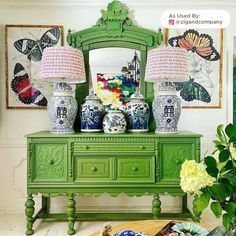 a green dresser topped with vases and lamps