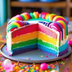 a rainbow cake is on a plate with sprinkles