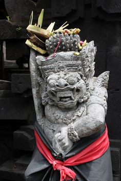 a stone statue with fruit on it's head in front of a black wall