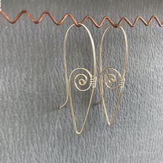 These lightweight earrings merge the classic spiral shape with the ear wire itself. The earrings are designed to hook into themselves, thus preventing them from coming out of your ears. The spiral is 14 kt. gold-fill, woven at the sides with Argentium sterling silver wire. Four sizes are available; one photo shows the general differences between them. As these earrings are individually made by hand, please allow for minor differences between the items shown and the ones you receive. Ear Wire Earrings, Everyday Spiral Earrings With Ear Wire, Swirl-shaped Earrings With Ear Wire, Nickel Free Spiral Earrings For Everyday, Nickel-free Spiral Earrings For Everyday, Everyday Spiral Nickel-free Earrings, Everyday Spiral Earrings For Pierced Ears, Everyday Nickel-free Spiral Earrings, Spiral Single Earring For Everyday Wear