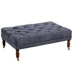 an upholstered footstool with wooden legs and buttons on the bottom end