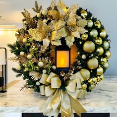 a christmas wreath on top of a table with a lit candle in the middle and decorations around it