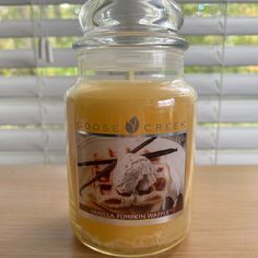 a glass jar filled with vanilla and pumpkin marmalade ice cream sitting on top of a wooden table