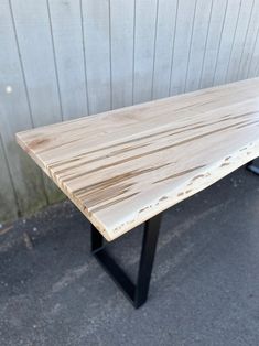 a wooden table sitting on top of a cement floor next to a wall with wood planks