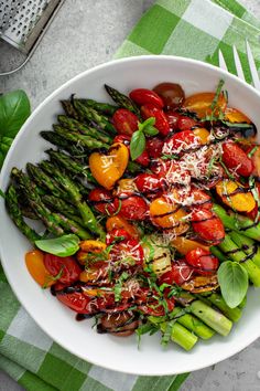 a white bowl filled with asparagus and tomatoes