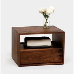 a vase with white flowers on top of a wooden shelf next to a tissue dispenser