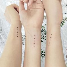 two women with matching tattoos on their arms and wrist, both have small dots in them