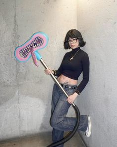 a woman holding a blow dryer in her right hand while standing next to a wall