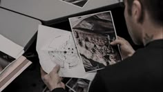 a man looking at pictures on top of a table