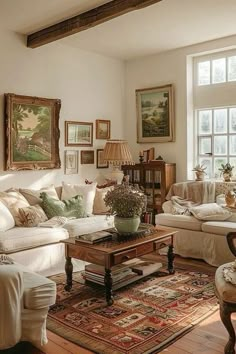 a living room filled with lots of furniture and paintings on the wall above it's windows