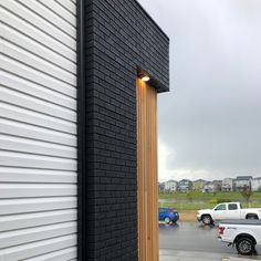 a white truck parked next to a tall black building with a light on it's side