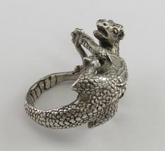 Presented is a fantastic signed sterling silver ring, by jewelry artist James Yesberger. This ring is made in the form of a dragon. The dragon is quite detailed and as lifelike as a mythical beast can be, with fine textured scales on both the dragon's back and belly. The dragon's tail stretches out and becomes the band of the ring, being gripped in the dragon's hands on the other side. The ring has a nice feeling of weight and substance on the hand, and is definitely an eye-catching piece. This Silver Fantasy Rings For Collectors, Collectible Dragon Design Jewelry Ring, Collectible Dragon Design Ring, Silver Dragon Design Jewelry For Formal Occasions, Unique Snake Ring With Dragon Design Gift, Unique Sterling Silver Ring With Dragon Design, Formal Silver Jewelry With Dragon Design, Silver Jewelry With Dragon Design For Formal Occasions, Collectible Symbolic Sterling Silver Snake Ring