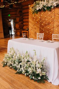 the table is set up with white flowers and greenery