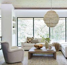 a living room filled with white furniture and lots of glass doors leading to the outside