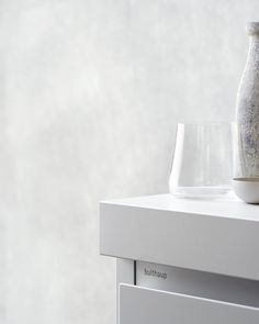 a vase sitting on top of a white cabinet next to a glass bowl and container