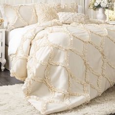 a white bed with ruffled sheets and pillows