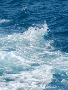 a person riding a surfboard on top of a wave in the ocean with blue water