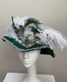 New women's Renaissance Medieval Elizabethan Victorian royal green brocade hat cap. This stunning brim hat is embellished with white ostrich feathers secured with a regal broach.  Brim is 2 1/2" wide secured by a beaded pearl cord. Brim trimmed with a silver braid. Fully lined. Great for your next theme party, stage production or Renaissance Faire. Sales final. New not worn. High Crown Hats For Carnival Costume, Curved Brim Costume Hat For Carnival, Victorian High Crown Costume Hat, Curved Brim Carnival Costume Hat, Curved Brim Hats For Carnival Costume, Curved Brim Costume Hats For Carnival Party, Victorian Brimmed Costume Hats And Headpieces, Victorian Brimmed Costume Hat, Victorian Curved Brim Costume Hat