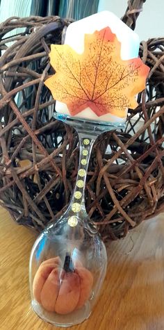 a glass vase with a leaf on it sitting on a table next to some branches