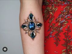 a woman's arm with a blue and green jeweled bracelet attached to it