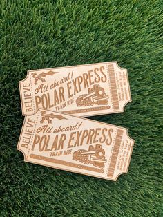 two tickets sitting on top of green grass with the words polar express printed on them