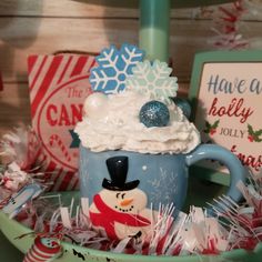 a cup filled with whipped cream sitting on top of a green bowl next to candy