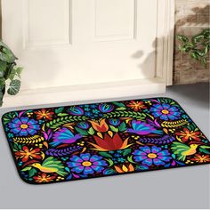 a door mat with colorful flowers and leaves on the floor next to a potted plant