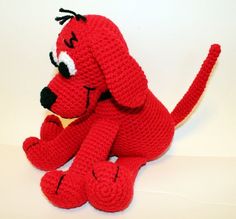 a crocheted red dog sitting on the floor