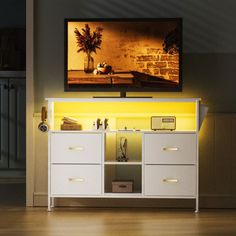 a white entertainment center with yellow lighting under a painting on the wall in a living room