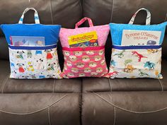 three bags sitting on top of a couch next to each other with books in them