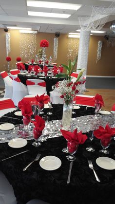 a black and white table cloth with red flowers on it is set for a formal function