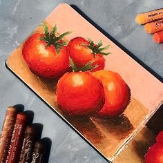 three tomatoes on a cutting board with crayons next to it and some pencils