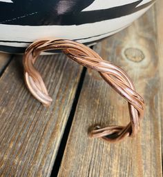 a metal bracelet sitting on top of a wooden table next to a black and white pillow