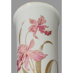 a white vase with pink flowers painted on the side and gold trimming around it