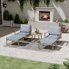 two chairs and a table sitting in front of a fire place with plants on it