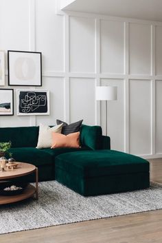 a living room with green couches and pictures on the wall above it, along with a coffee table