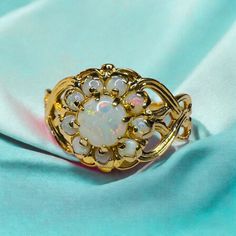 FREE SAME DAY SHIPPING & GIFT WRAPPING! A beautiful Vintage Opal Flower Halo Cabochon Ring! This alluring 10kt gold vintage ring holds 10 opals, main 5x5mm and 2.3x1.2mm halo opals along a stylish prong setting. The stones are simply mesmerizing, displaying an array of iridescent colors that flash and shimmer! A variety of colorful shades are included in the color play, almost seeming to glow from within. Completing the design are the ornate twisted shoulders, which extend to a smooth gold band Yellow Gold Multi-stone Flower Ring For Wedding, Heirloom White Jewelry With 17 Jewels, Antique White Multi-stone Rings, Gold Opal Ring With 17 Jewels, White 14k Gold Flower Ring Fine Jewelry, White Round Cluster Ring Hallmarked, Antique Opal Jewelry In Yellow Gold, Antique Opal Wedding Rings, Victorian Multi-stone White Jewelry